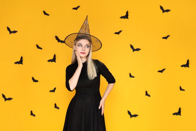 Concept of Halloween, young woman on yellow background