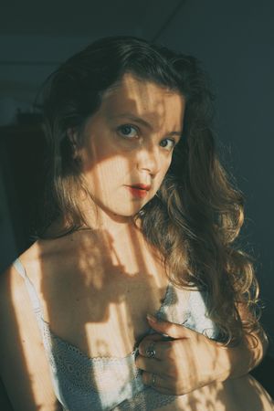 Portrait of mature woman in gray bra with floral shadow from the window