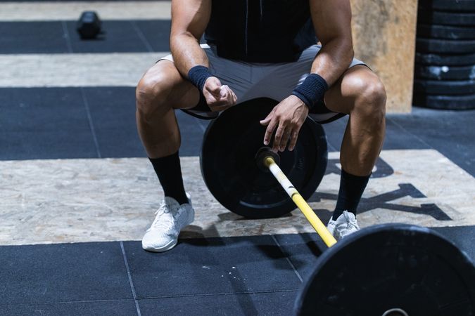 Strong anonymous sportsman near barbell