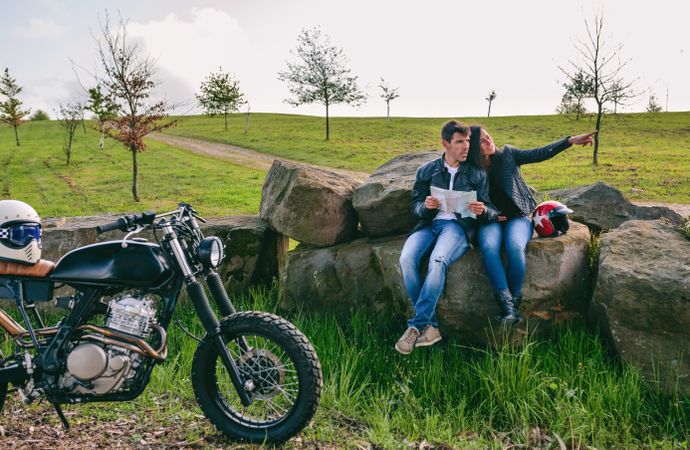 Couple sitting looking at a map with motorcycle