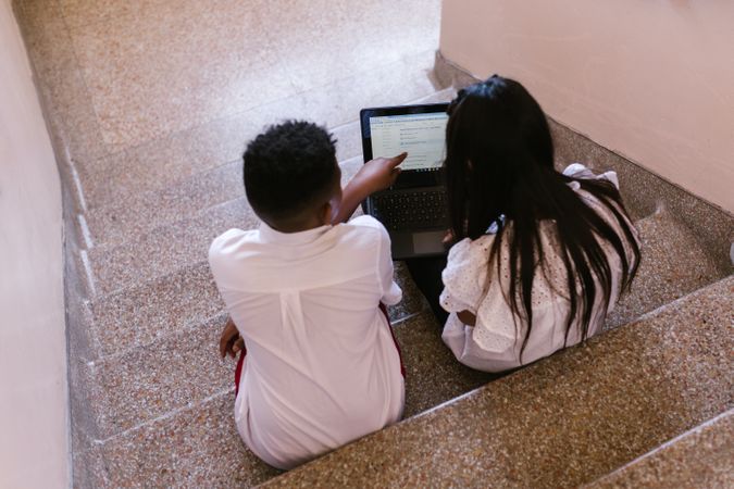 Back view of girl and boy with laptop in school