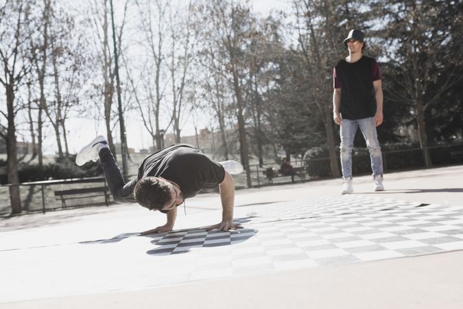 Guy looking at man dancing break dance in park