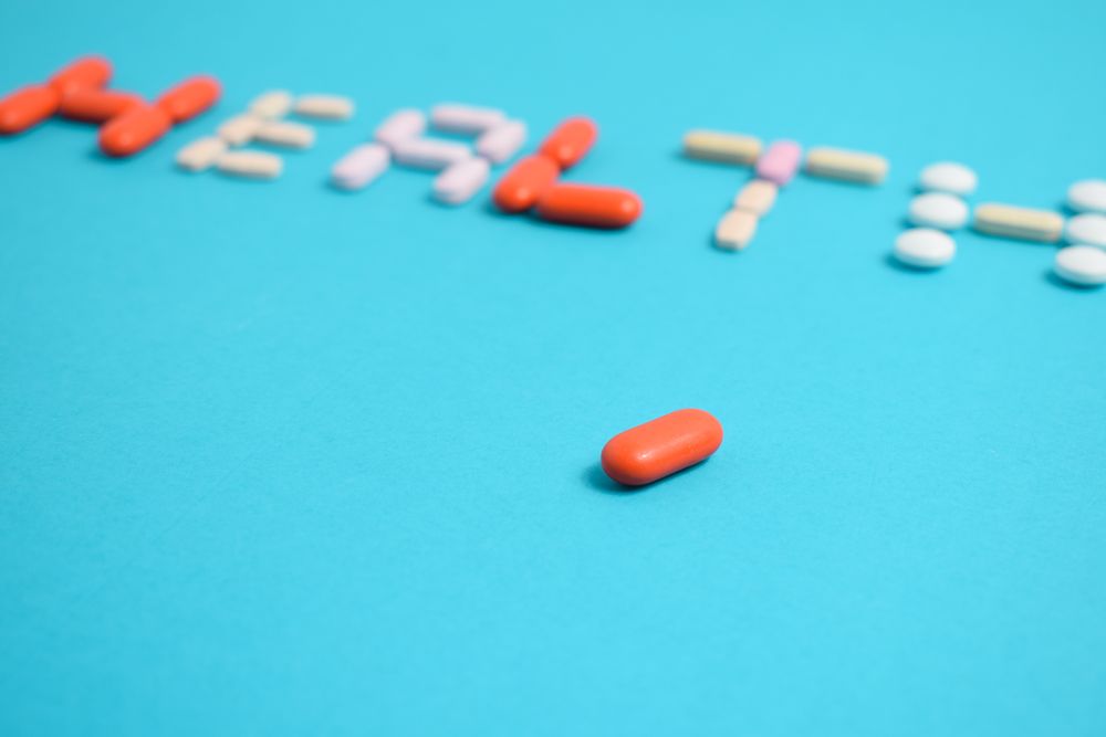 Pills spelling the word "HEALTH" on blue background