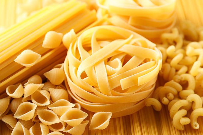 Different pasta as background, closeup. Dry uncooked whole pasta