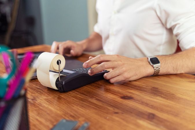 Businessman using a printing calculator for accounting at an office desk.