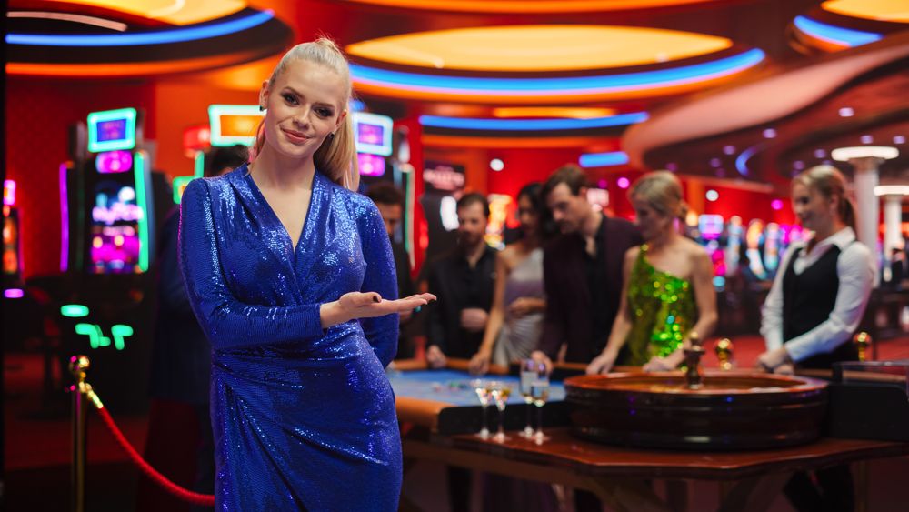 Portrait of a Young Woman Wearing a Glittering Blue Dress, Standing in a Modeling Pose and Gesturing at an Empty Space for a Company Slogan