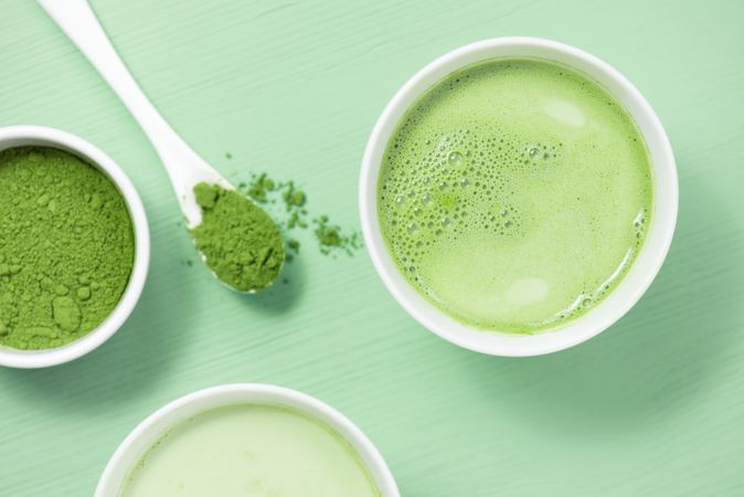 Top view of green tea on green table with spoon of matcha