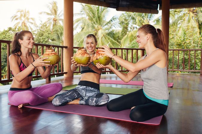 Group of female having coconut juice during break at yoga class