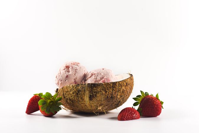 Side view of coconut shell with strawberry ice cream and fruit halves
