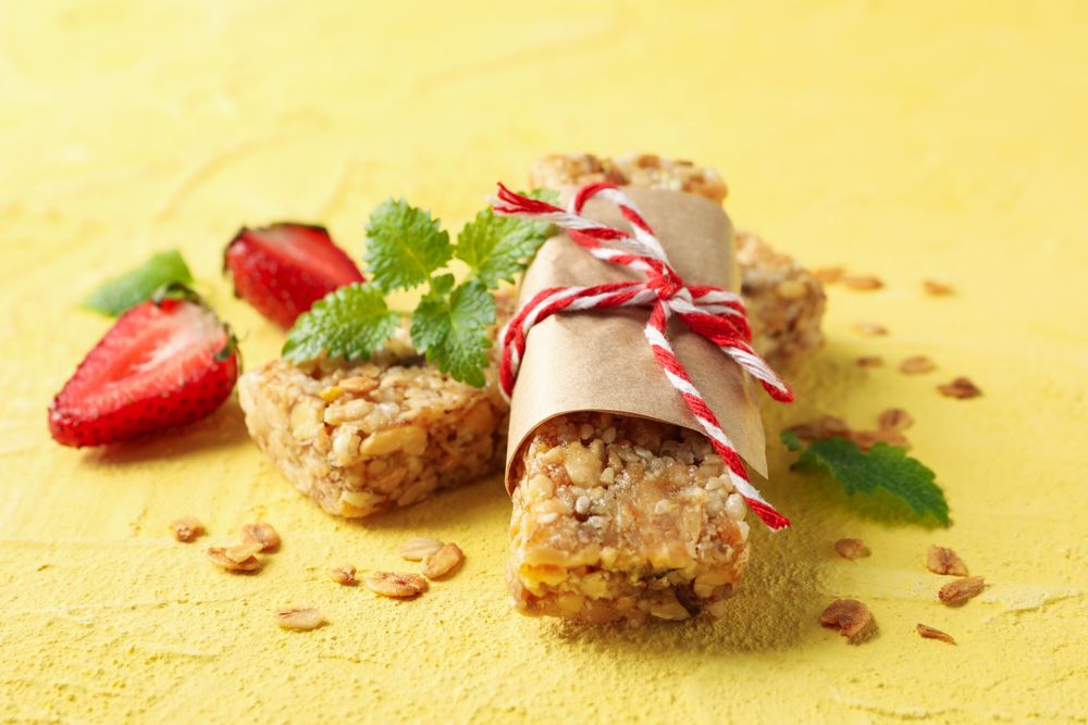 Tasty granola bars on yellow background, close up