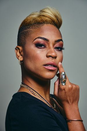 Portrait of serious Black woman with short blonde hair and hand to her face