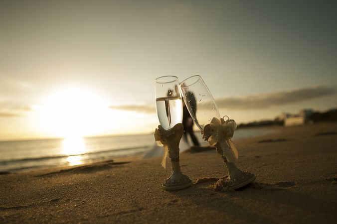 Woman and man embracing on seashore with glasses of champagne