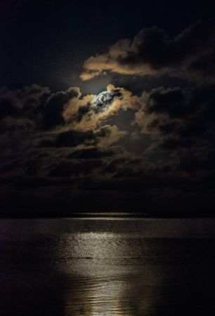 Full moon behind clouds above Indian Ocean