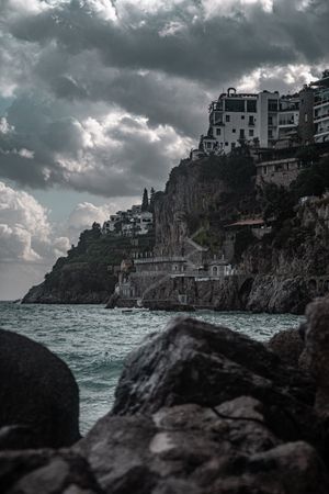 Grayscale photo of a town by the sea during cloudy day