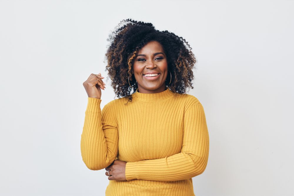 Studio shot of a confident Black woman in yellow shirt looking at camera