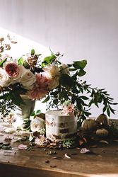 plate with cake decorated flower on table with bouquet of blooms in vase