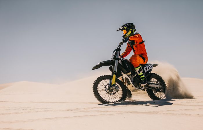 Motocross biker driving bike over sand dunes
