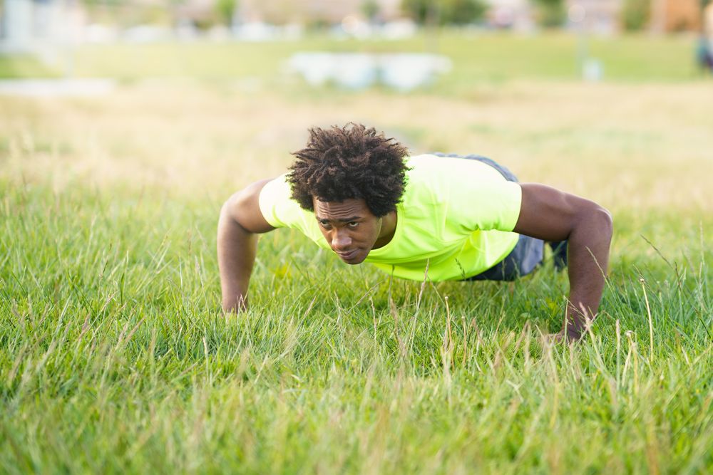 Man in neon shirt doing pushups outside