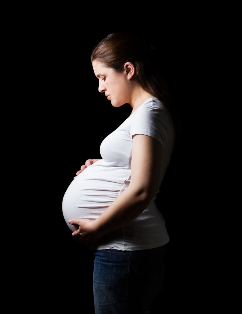 Beautiful expectant pregnant woman looking her belly isolated