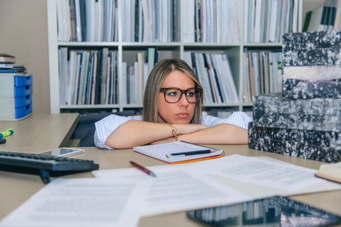 Exhausted woman next to box of documents in office