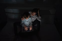 Mother helping son to do homework in darkness