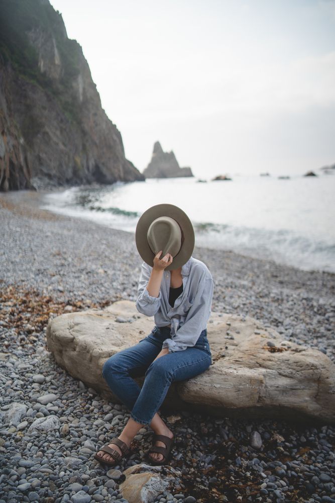 Woman resting on beach stone by sea