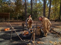 Two people reenact preparing a meal in the 1600s at  Powhatan Indian Village, Jamestown, Virginia