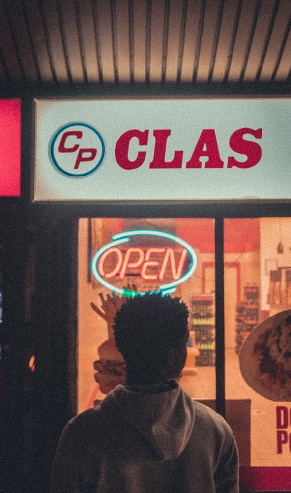 Back view of young man in front of store at night