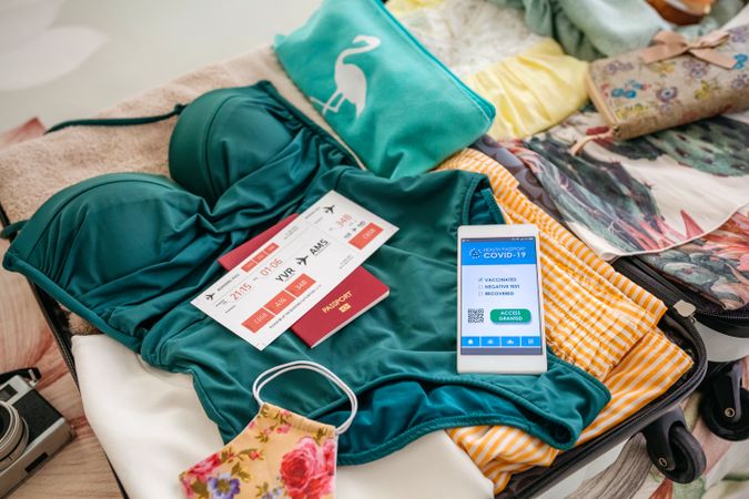Open suitcase with woman luggage for beach vacation and covid passport