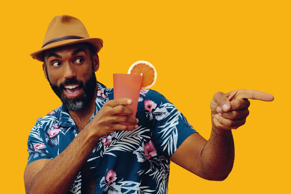 Excited male giving pointing away while wearing colorful shirt with yellow background