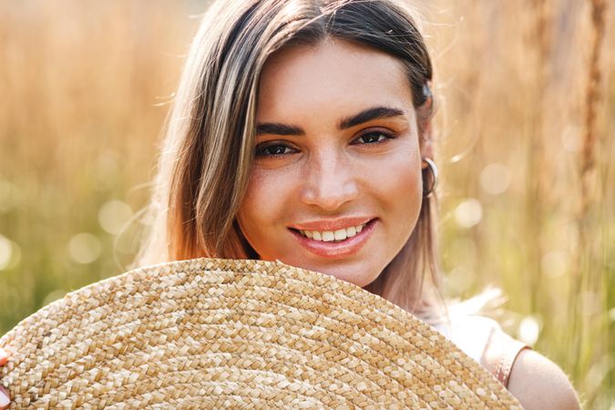 Portrait of woman smiling behind a straw hat