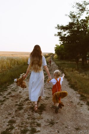 Anonymous young mother with little sons walking near wheat field in countryside