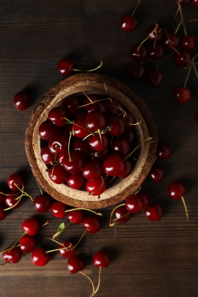 Ripe cherry fruits in a bowl on a wooden background