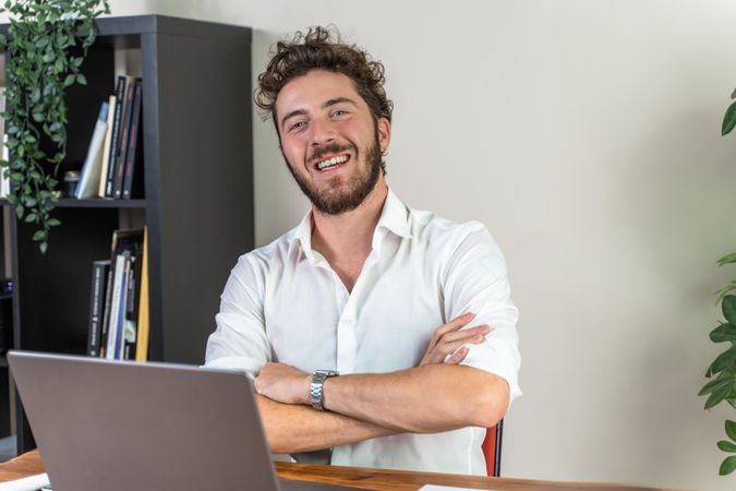 Confident young businessman smiling at the camera in his office.