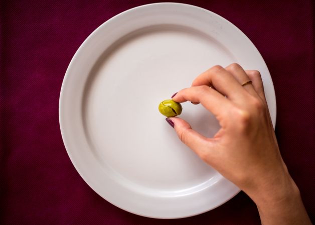 Faceless woman eating olive in restaurant