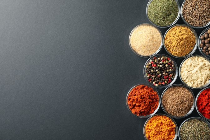 Rows of bowls of spices on dark table, copy space