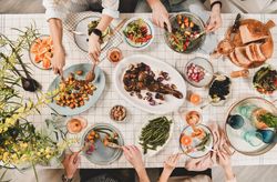 Flat-lay of Mediterranean table setting, with group of people at dinner table