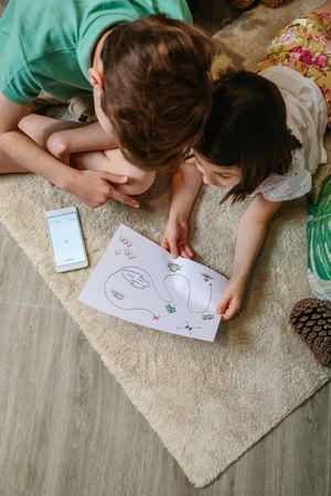 Top view of kids playing treasure hunt at home on the carpet