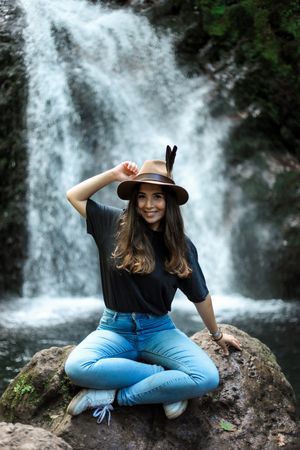 Smiling woman sitting near waterfall