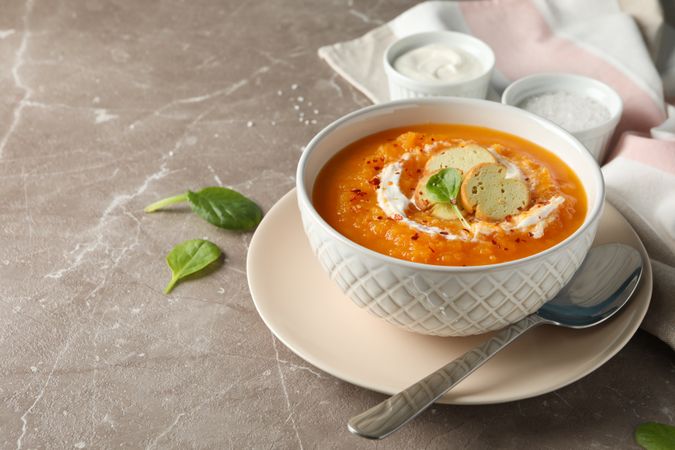 Bowl of pumpkin soup on marble counter with copy space