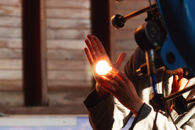 Man's hand illuminated by bright telescope light reflection.