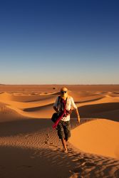 Anonymous traveler in desert during sunset