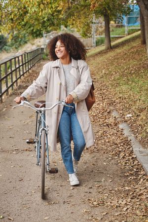 Happy female walking with bike in countryside