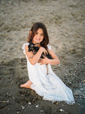 Girl with little dog on sandy beach