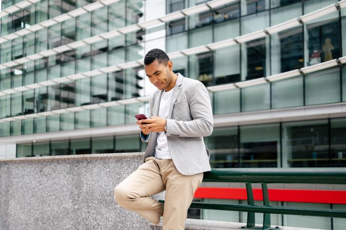 Man using smartphone leaning against wall