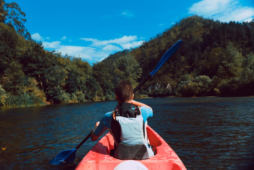 Female kayaking with paddle in raised hands