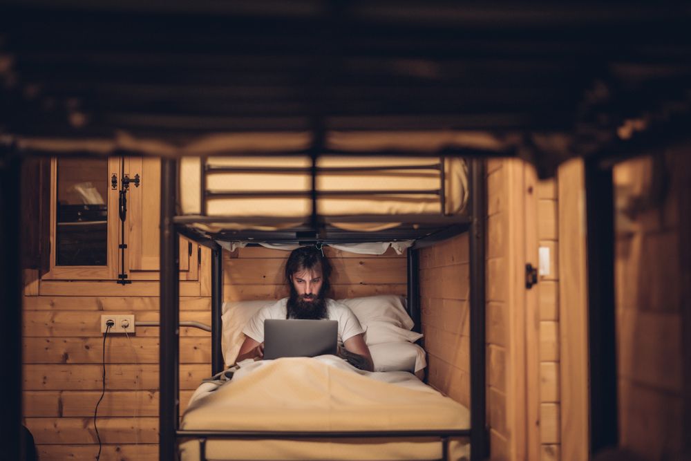 Man using laptop in rustic bunk bed