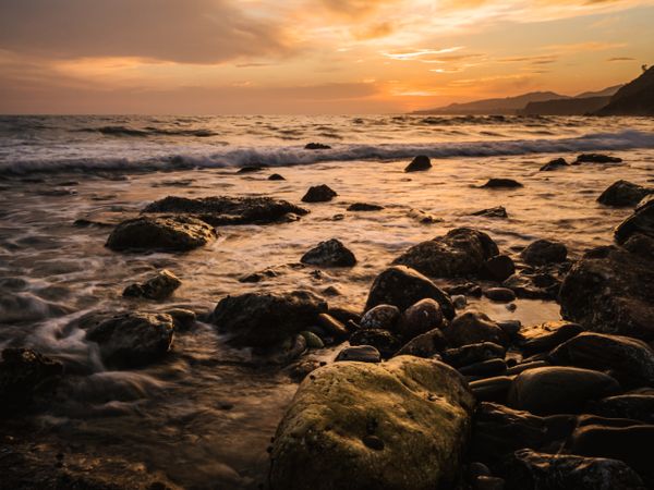 Stony seashore and waves at beautiful sunset