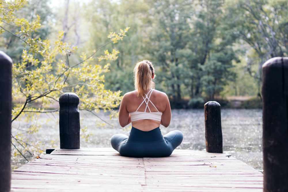 Woman meditating in nature near a lake