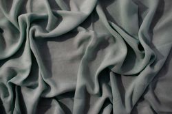 Nude green fabric wavy crumpled background texture with copy space.